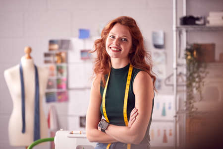 Portrait Of Female Student Or Business Owner With Tape Measure Working In Fashion Sitting On Deskの写真素材