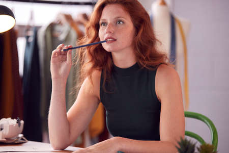 Thoughtful Female Student Or Business Owner Working In Fashion Sketching Designs In Studioの写真素材