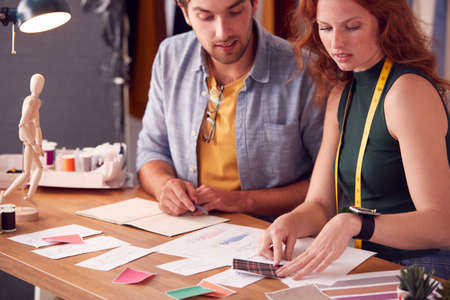 Male And Female Students Or Business Owners Working On Designs In Fashion Studio Togetherの写真素材