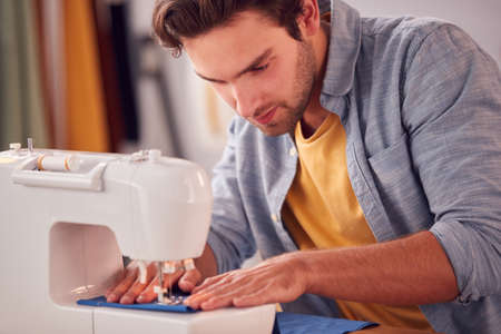 Close Up Of Male Student Or Business Owner Working In Fashion Using Sewing Machine In Studioの写真素材