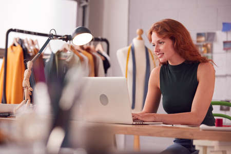 Female Student Or Business Owner Working In Fashion Using Laptop In Studioの写真素材