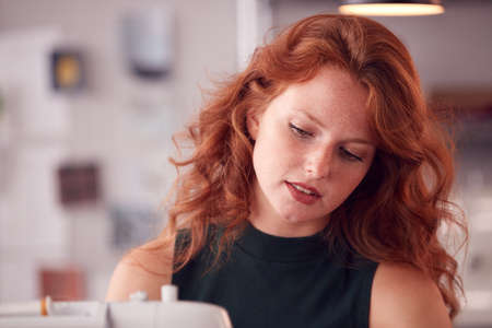 Close Up Of Female Student Or Business Owner Working In Fashion Using Sewing Machine In Studio