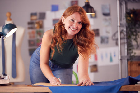Female Student Or Business Owner Working In Fashion Drawing Pattern On Fabric In Chalkの写真素材