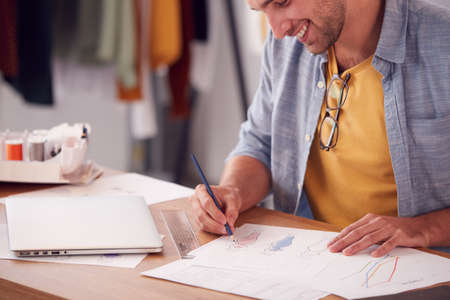 Close Up Of Male Student Or Business Owner Working In Fashion Sketching Designs In Studio