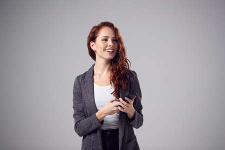Studio Portrait Of Smiling Young Businesswoman With Folded Arms Against Plain Backgroundの写真素材