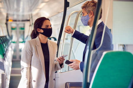 Business Commuters Stand In Train Carriage With Mobile Phones Wearing PPE Face Masks During Pandemicの写真素材