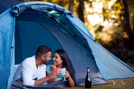 Camping Couple Lying In Tent Drinking Champagne Togetherの写真素材