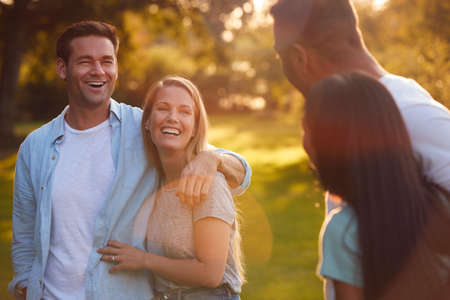 Group Of Friends On Walk In Countryside Against Flaring Sun