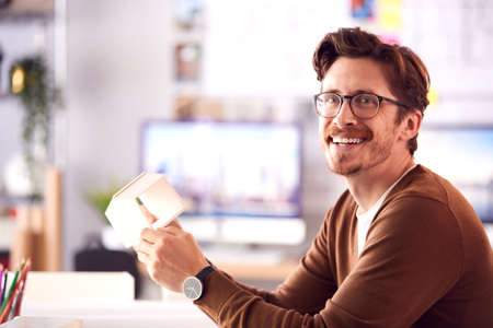 Portrait Of Male Architect In Office Working At Desk With Wooden Model Of Buildingの写真素材