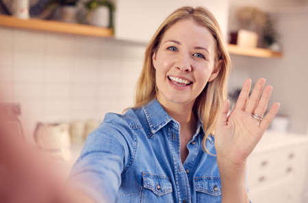 POV Shot Of Female Vlogger Holding Mobile Phone Camera Making Social Media Video At Homeの写真素材