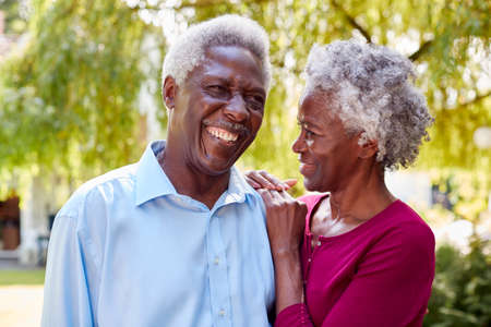Portrait Of Loving Senior Couple Standing In Garden At Home After Retirement