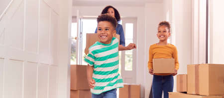 Children Helping Mother To Carry Boxes Into New Home On Moving In Dayの写真素材