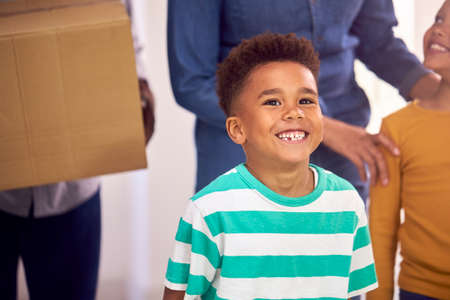 Close Up Of Children Helping Parents To Carry Boxes Into New Home On Moving In Dayの写真素材