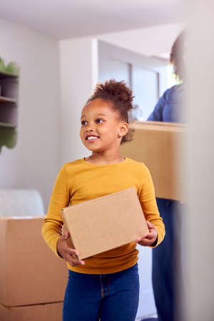 Girl Helping Mother To Carry Boxes Into New Home On Moving In Dayの写真素材