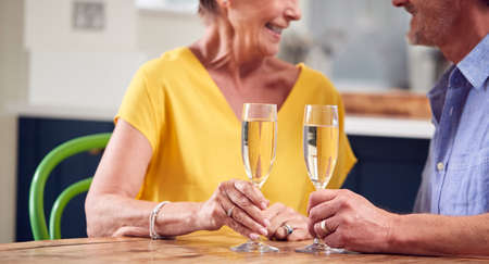 Close Up Of Retired Couple Celebrating With Glass Of Champagne At Home On Date Night Togetherの写真素材