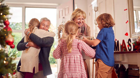 Grandchildren Greeting Grandparents As They Arrive With Presents To Celebrate Family Christmasの写真素材
