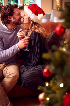 Loving Couple Celebrating With Champagne Around Christmas Tree At Homeの写真素材