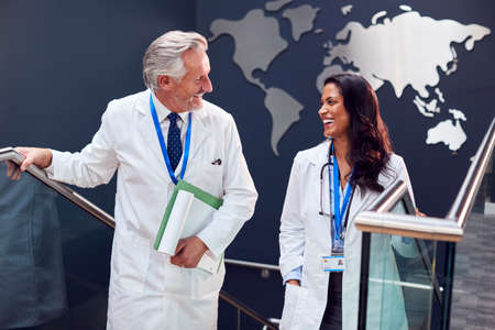 Two Doctors Wearing White Coats Have Informal Meeting In Hospital