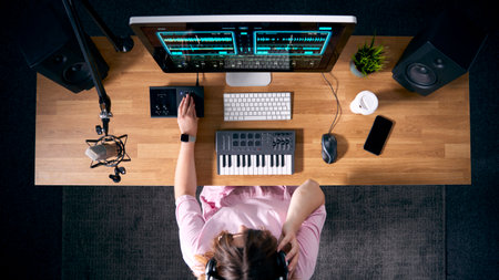 Overhead View Of Female Musician At Workstation With Keyboard And Microphone In Studioの写真素材