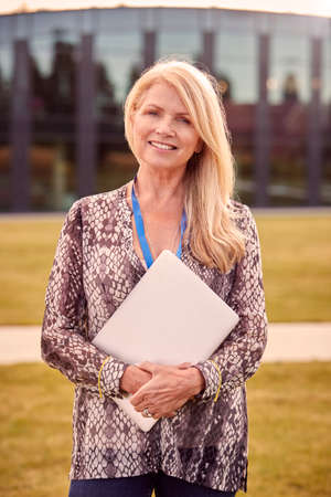 Portrait Of Female University Or College Tutor Outdoors With Modern Campus Building In Backgroundの写真素材