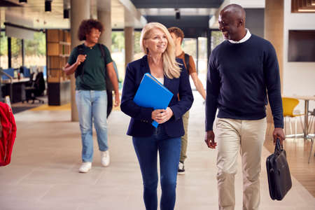 Male And Female Tutors In Busy University Or College Building With Studentsの写真素材