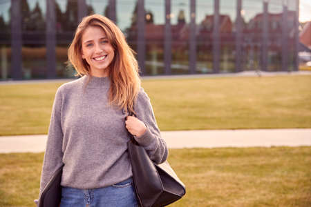 Portrait Of Female University Or College Student Outdoors With Modern Campus Building In Backgroundの写真素材
