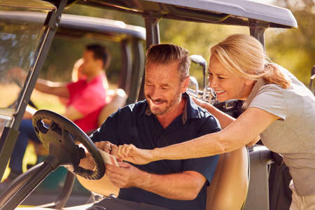 Mature And Mid Adult Couples In Buggies Playing Round On Golf Togetherの写真素材