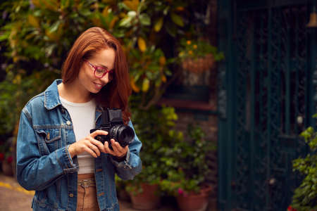 Young Woman In City Taking Photo On Retro Medium Format Film Camera To Post To Social Mediaの写真素材
