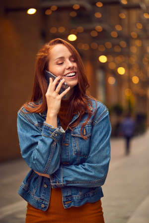 Female Vlogger Travelling Through City Making Phone Call On Mobile Phone On Streetの写真素材