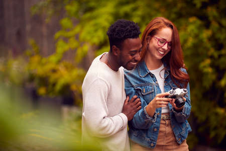 Couple In City Taking Photo On Retro Film Camera To Post To Social Mediaの写真素材