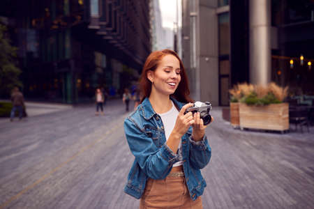 Young Woman In City Taking Photo On Digital Camera To Post To Social Media