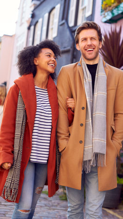 Multi Cultural Couple With Friends Walking Along Residential City Street In Fall Or Winterの写真素材