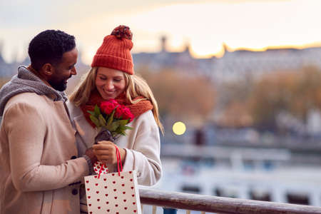 Couple In Autumn Or Fall Meeting On Date In City With Man Giving Woman Bouquet Of Flowersの写真素材
