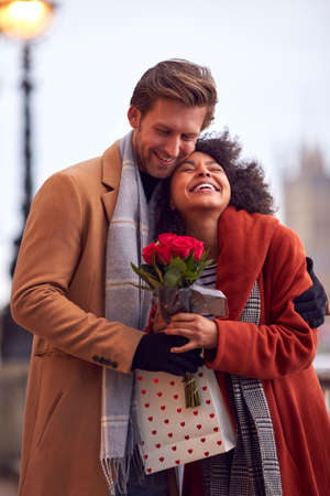 Couple In Autumn Or Fall Meeting On Date In City With Man Giving Woman Bouquet Of Flowersの写真素材