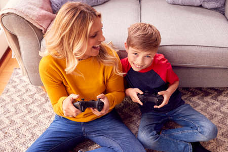 Mother And Son Sitting On Lounge Floor At Home Playing Video Game Togetherの写真素材