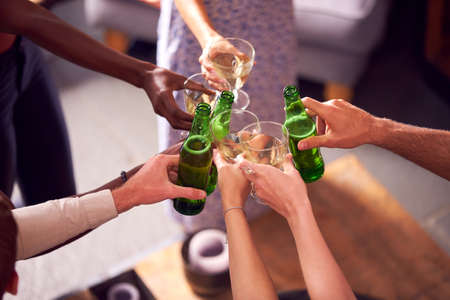 Close Up Of Friends In Lounge At Home Making A Toast With Beer And Wineの写真素材