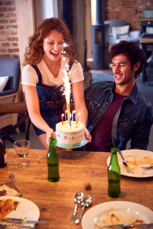 Multi-Cultural Group Of Friends Celebrating Birthday With Party And Cake At Home Together
