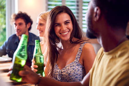 Multi-Cultural Group Of Friends Enjoying Beer And Takeaway Food At Home Together