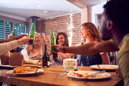 Multi-Cultural Group Of Friends Celebrating Birthday With Party And Cake At Home Togetherの写真素材