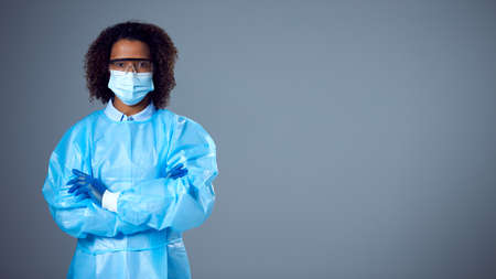 Studio Portrait Of Female Lab Worker in PPE With Face Mask And Safety Glasses Looking At Camera
