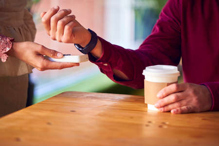Close Up Of Man Making Contactless Purchase In Coffee Shop Using Smart Watchの写真素材