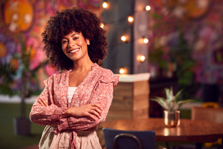Portrait Of Smiling Female Server Working Night Shift In Bar Restaurant Or Clubの写真素材