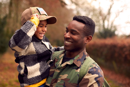 American Soldier In Uniform Returning Home To Family On Leave With Son Wearing Army Cap