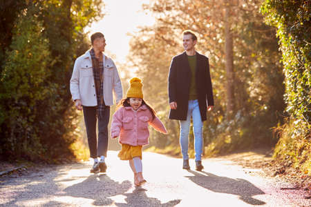 Family With Two Dads Taking Daughter For Walk In Fall Or Winter Countrysideの写真素材