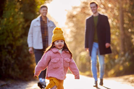 Family With Two Dads Taking Daughter For Walk In Fall Or Winter Countrysideの写真素材