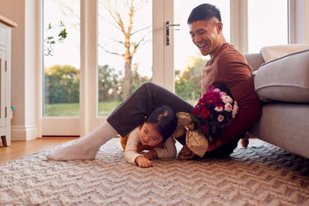Family At Home With Dad Being Given Bunch Of Flowers On Birthday By Daughterの写真素材