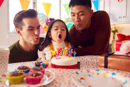 Family With Two Dads Celebrating Daughter's Birthday At Home With Cake And Partyの写真素材