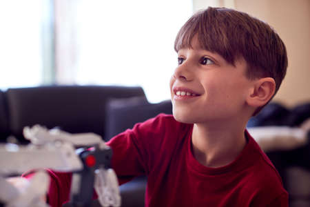Boy Wearing Pyjamas Building Robotic Arm From Plastic Kit At Homeの写真素材