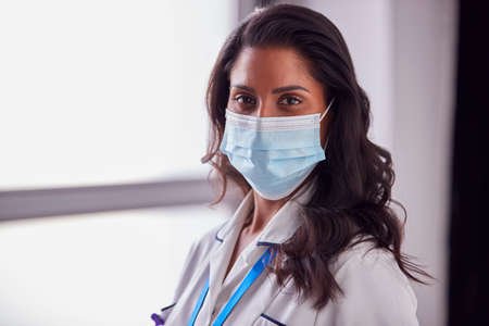 Portrait Of Female Mature Nurse In Uniform Wearing Face Mask In Hospitalの写真素材