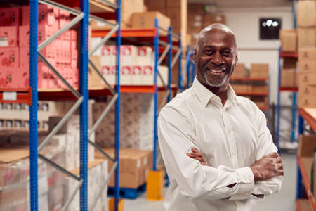 Portrait Of Male Team Leader Standing By Shelves In Warehouseの写真素材